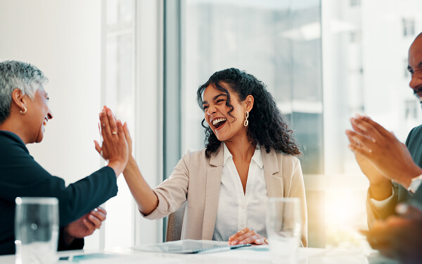 Two women high-five with finance documents in front of them.
